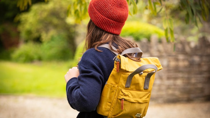 A woman wearing a mustard colour ROKA backpack